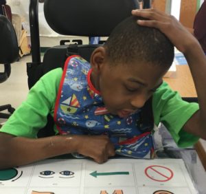 Student looking over a universal core board on a table in front of him