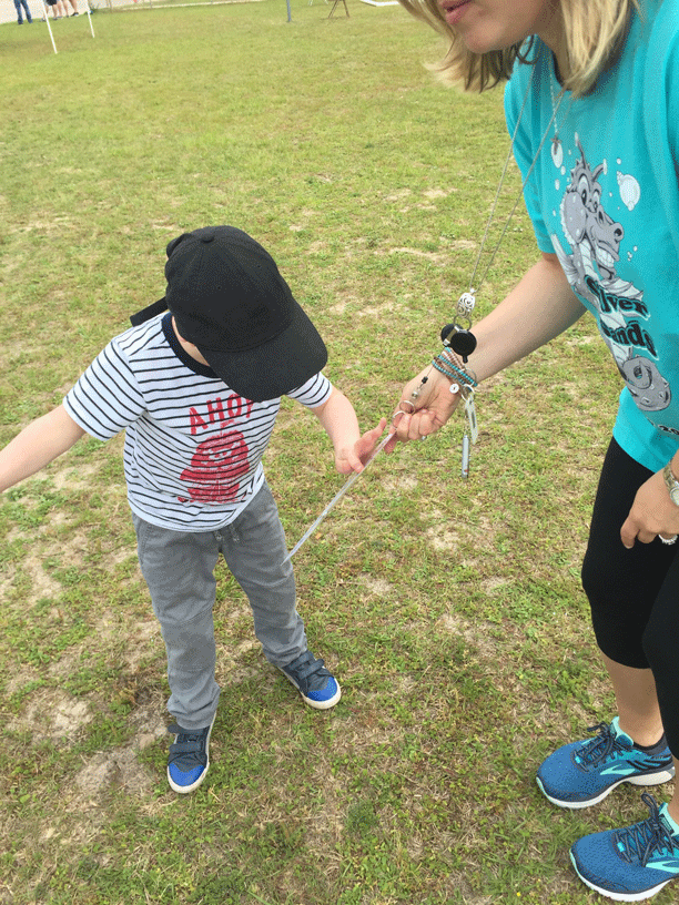 a teacher showing a student a core vocabulary board attached to a lanyard